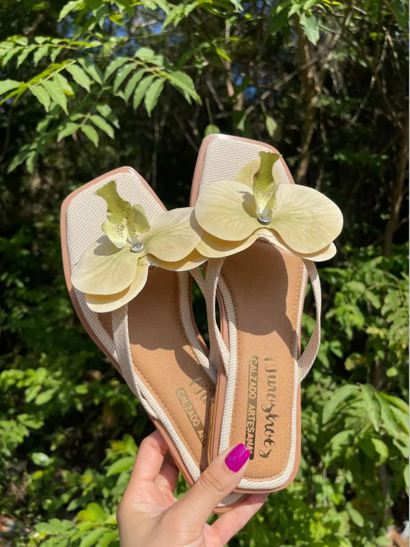Sandalias con flor de orquídea sobre fondo de jardín